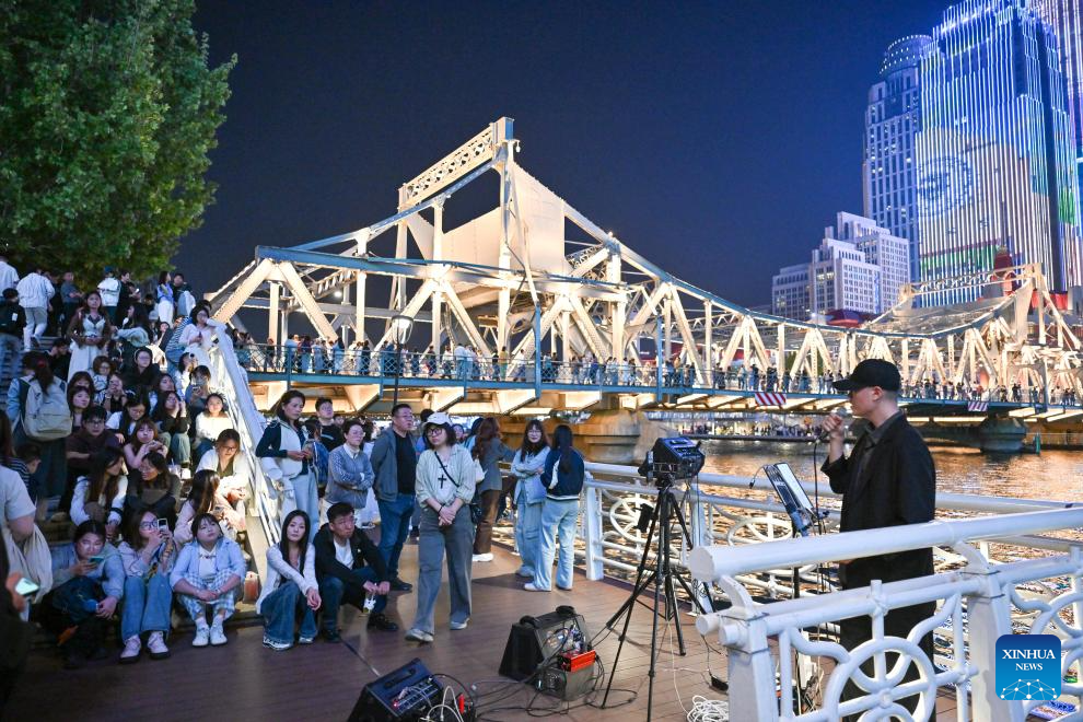 Pelancong menonton persembahan nyanyian di tepi Sungai Haihe di Tianjin, utara China, 24 April 2026. (Xinhua/Sun Fanyue)