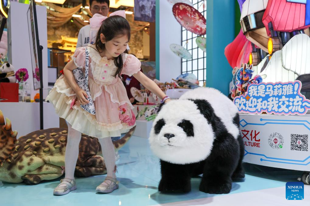 Seorang budak perempuan berinteraksi dengan panda robot pada Pameran Industri Budaya Antarabangsa China ke-22 di Shenzhen, provinsi Guangdong, selatan China, 24 Mei 2026. (Xinhua/Liang Xu)