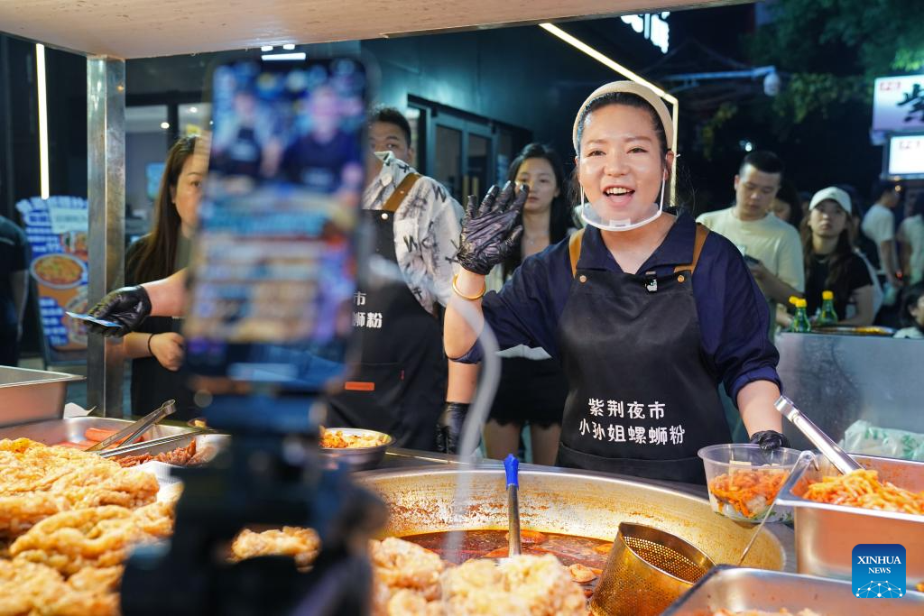 Wu Jia, seorang pemilik gerai, berinteraksi dengan netizan melalui strim langsung di Pasar Malam Zijing di Zon Pembangungan Ekonomi Nanchang, provinsi Jiangxi, timur China, 12 Mei 2026. (Xinhua/Wan Xiang)
