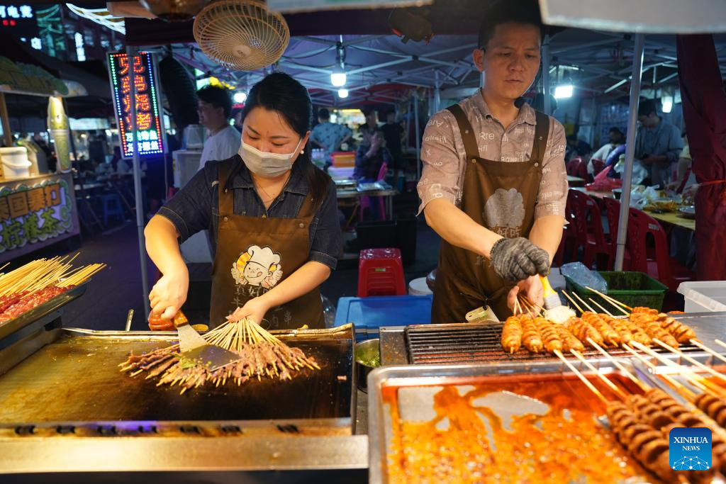 Xiong Yuanbo (kanan) dan Li Tian menyediakan barbeku untuk pelanggan di Pasar Malam Zijing di Zon Pembangungan Ekonomi Nanchang, provinsi Jiangxi, timur China, 12 Mei 2026. (Xinhua/Wan Xiang)