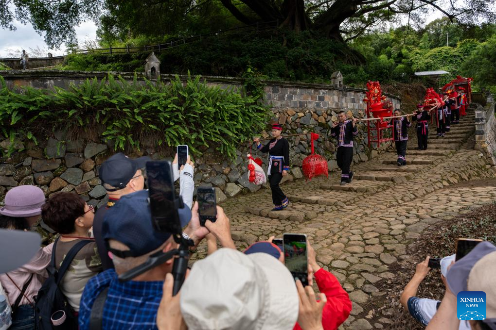 Pelawat melihat dan mengambil gambar pertunjukan upacara perkahwinan etnik She di kampung Banyueli, kaunti Xiapu, bandar Ningde, provinsi Fujian, tenggara China, 10 Jun 2026. Ritual ini termasuk dalam senarai warisan budaya tak ketara negara. (Xinhua/Zhang Xiaoyu)