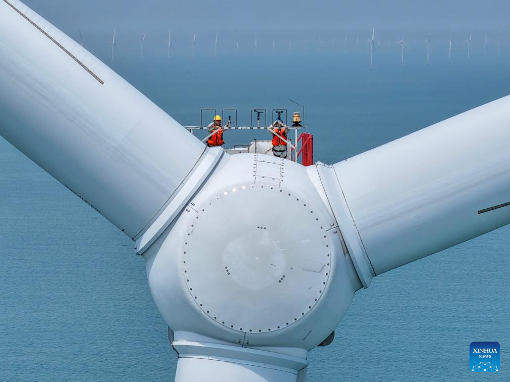 A drone photo taken on June 10, 2026 shows maintenance workers conducting routine maintenance on a wind turbine at an offshore wind farm in Rudong, east China's Jiangsu Province. (Photo by Xu Congjun/Xinhua)