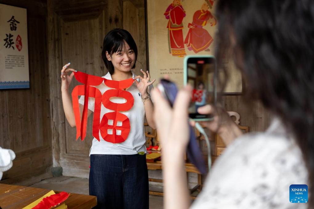 Seorang pengaudio siar menunjukkan seni guntingan kertas gaya etnik She di kampung Banyueli, kaunti Xiapu, bandar Ningde, provinsi Fujian, tenggara China, 10 Jun 2026. (Xinhua/Zhang Xiaoyu)