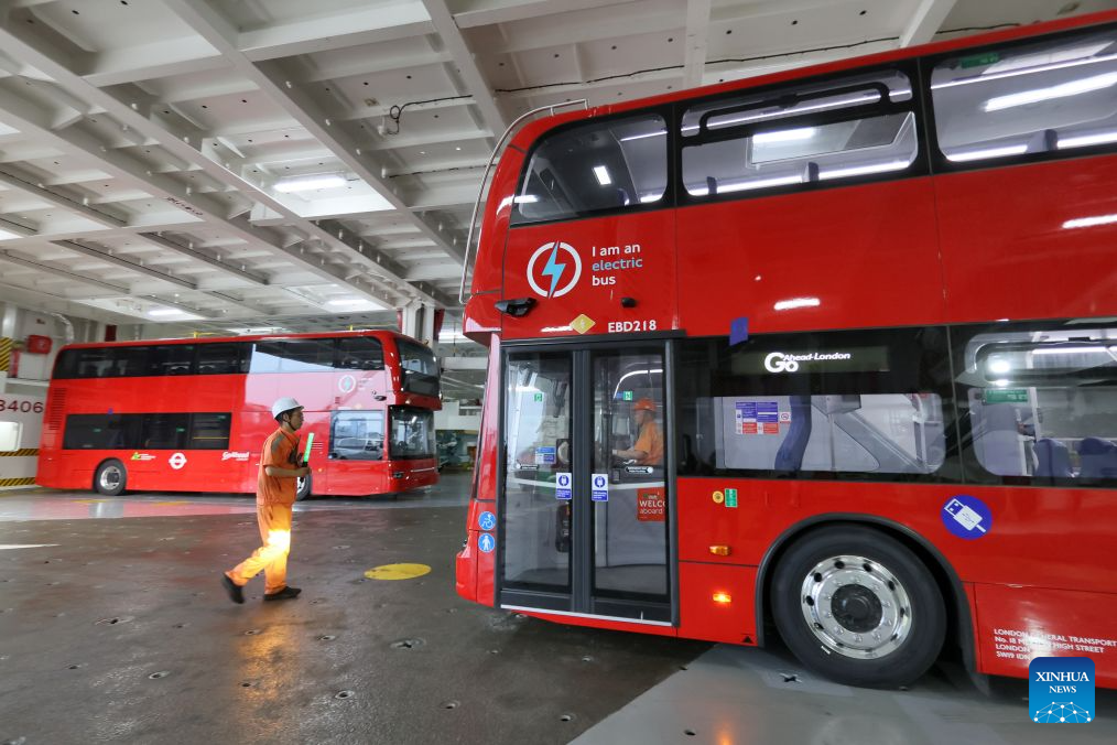 Seorang pekerja membantu pemandu meletakkan bas dua tingkat elektrik buatan domestik ke dek pengangkut kenderaan di Pelabuhan Yantai, provinsi Shandong, timur China, 5 Julai 2026. (Foto oleh Tang Ke/Xinhua)